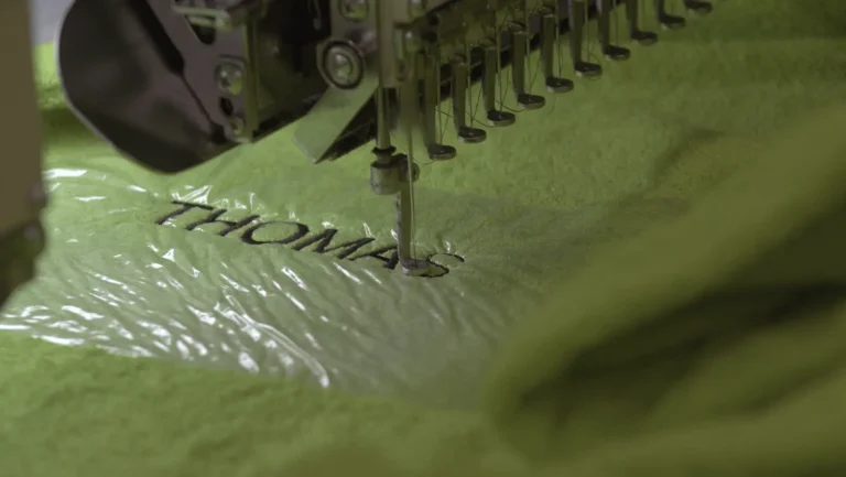 Prénom Thomas brodé sur un peignoir vert, sous l’aiguille de la machine