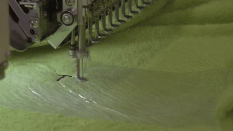 Machine à broder qui commence le prénom Thomas sur un peignoir vert