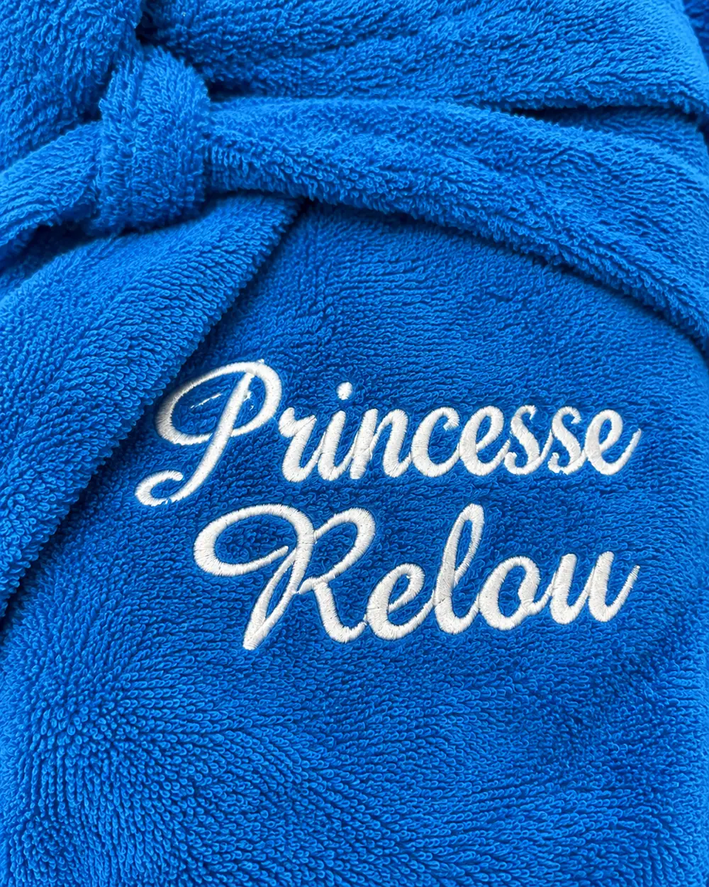 « Princesse Relou » brodé sur deux lignes en fil blanc sur une éponge bleue