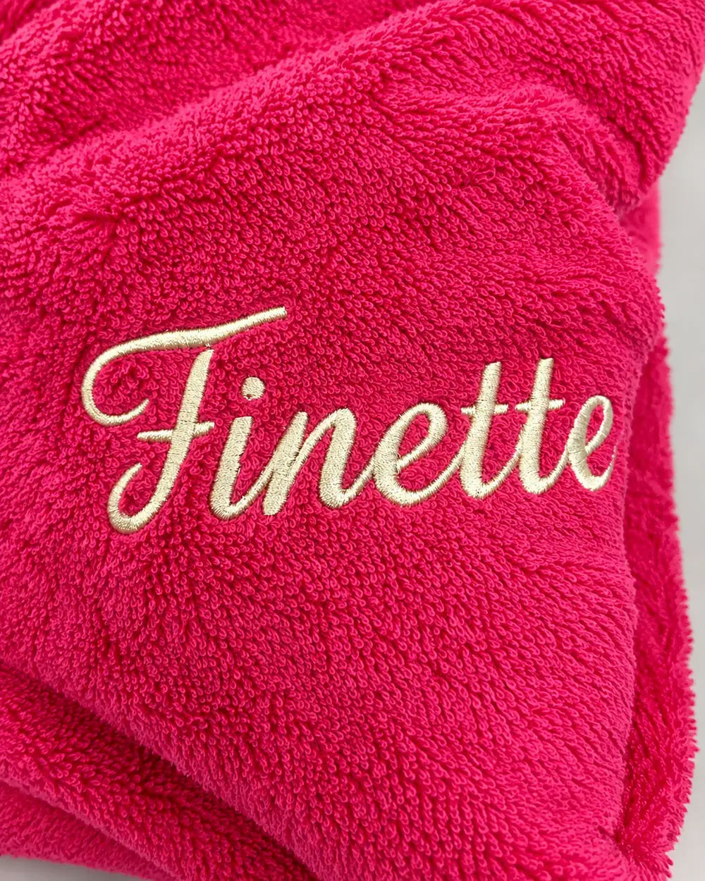 Surnom « Finette » brodé en fil écru sur une éponge fuchsia