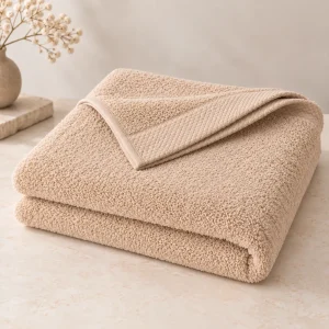 Drap de bain personnalisé beige, plié sur un plan de toilette