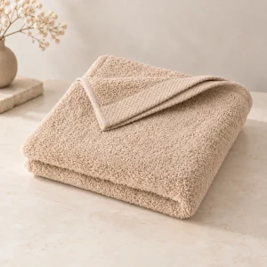 Serviette de bain personnalisée beige, pliée sur un plan de toilette